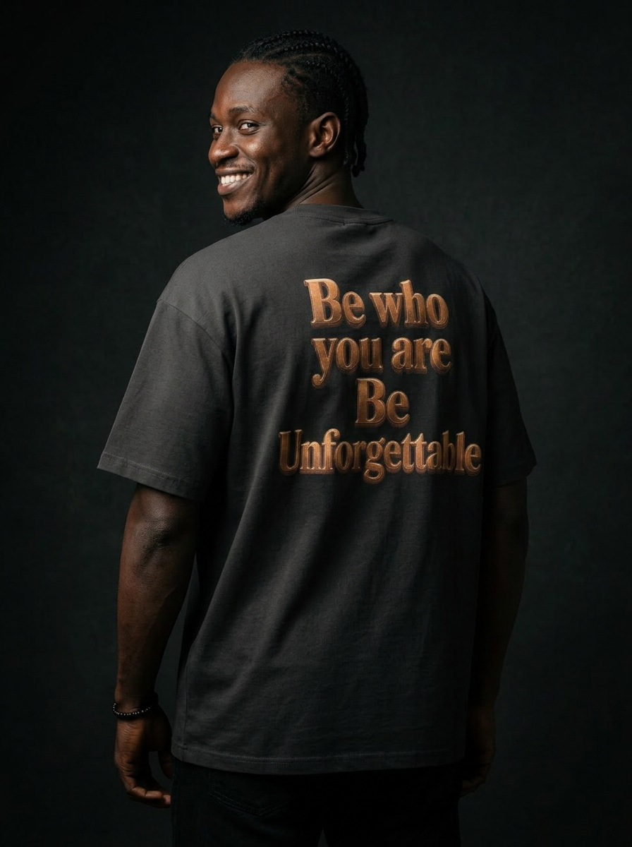 Model wearing the MR. HAPPINESS Statement Oversized T-Shirt back view showing the bronze "Be who you are · Be Unforgettable" artwork